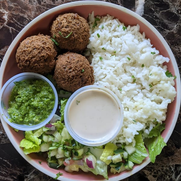 Tastee Grill's falafel plate with rice, salad, green sauce, and tahini dressing.