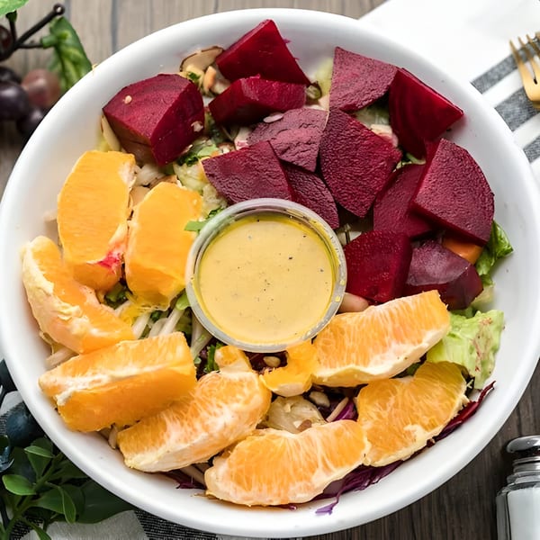 Tastee Grill's vibrant salad with beets, orange segments, and dressing in a white bowl.